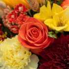 A close-up of an orange rose in a fall floral arrangement.