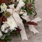 A close-up of an ivory ribbon bow in a fall candle floral centerpiece.