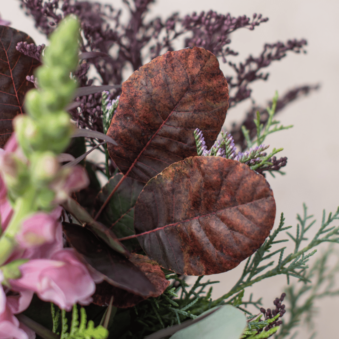 A close-up of burgundy smokebush leaves in a berry-toned bouquet.