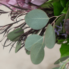 A close-up of sage eucalyptus leaves in a berry-toned bouquet.