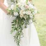 Elegant bridal bouquet with white and pink roses, greenery, and lace ribbon.
