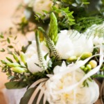 Elegant bouquet with white flowers, lush greenery, and ribbon, perfect for weddings or special occasions.